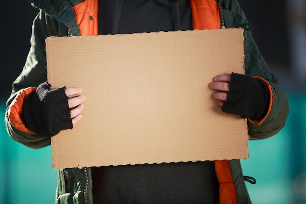 Morador de rua segurando papelão em branco para seu texto