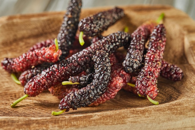 morango afegão preto e vermelho em colher de madeira em fundo de madeira cinza