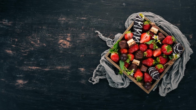 Morango com chocolate em uma caixa de madeira Em um fundo de madeira Vista superior Copiar espaço