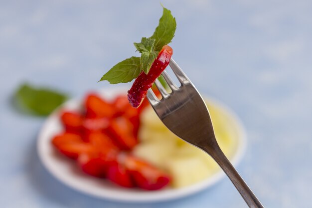 Morango em um garfo close-up. Salada de frutas vegetariana orgânica fresca num prato. Alimentação saudável . Nutrição adequada, dieta fitness.