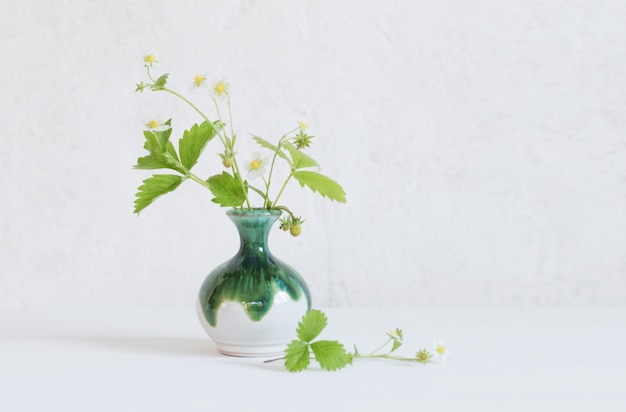 Morango flores em um vaso na mesa de madeira branca