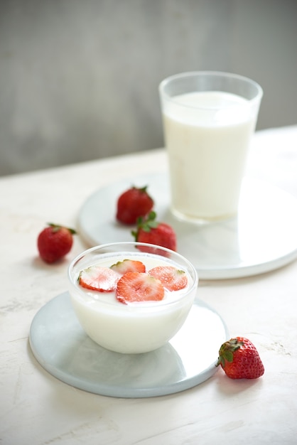 Morango fresco em um copo com iogurte de sobremesa e morango no fundo branco