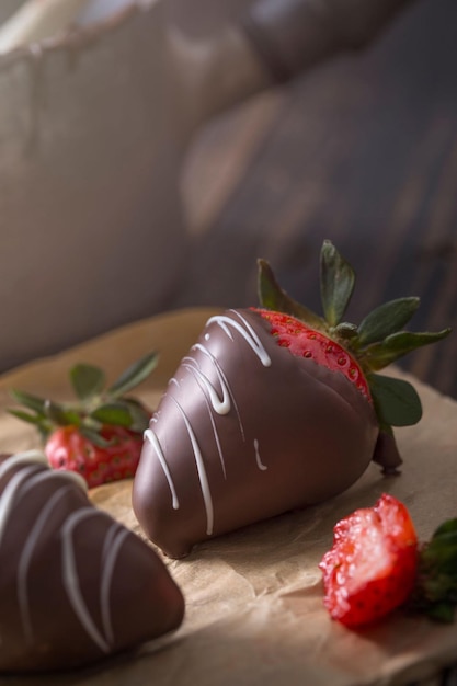 Foto morangos cobertos de chocolate na mesa de madeira rústica com chocolate ao leite escuro e chocolate branco