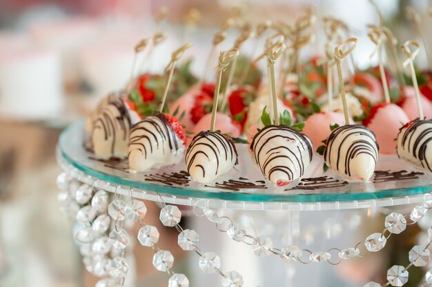 Morangos com chocolate ao leite. Morangos em um suporte de vidro decorado com contas de cristal. Sobremesa de casamento requintada. Sobremesa Vegetariana.