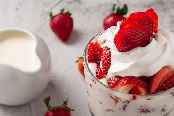 Foto morangos com creme em um copo de vidro em uma mesa de cimento espaço de cópia