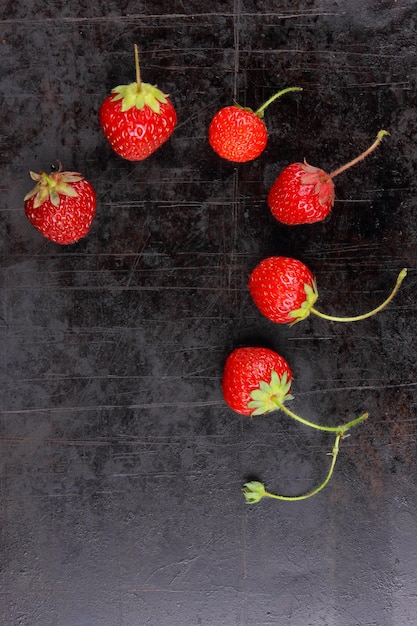 Morangos doces suculentos vermelhos com galhos em um fundo preto Closeup de frutas vermelhas Conceito de comida saudável