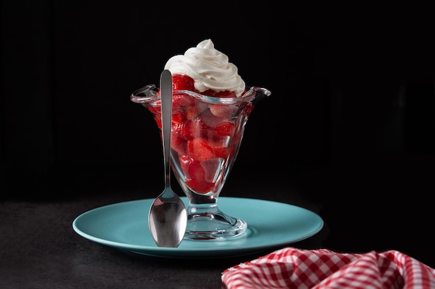 Morangos e chantilly em copo de sorvete em fundo preto