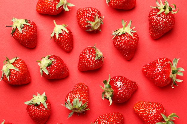 Morangos maduros e suculentos em um fundo vermelho. padronizar. Composição de fundo de verão criativo com morango. Conceito mínimo de fruta.