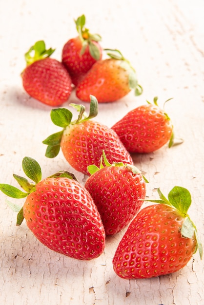 Morangos, vários morangos bonitos em uma prancha de madeira velha e desgastada, foco seletivo.