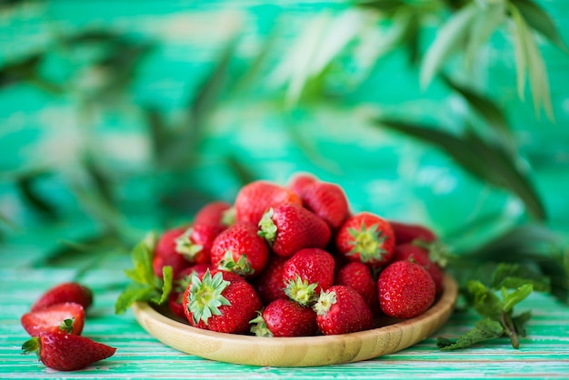 Morangos vermelhos frescos em um prato em um fundo rústico, frutas vermelhas sazonais, foco seletivo