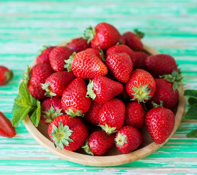 Morangos vermelhos frescos em um prato em um fundo rústico, frutas vermelhas sazonais, foco seletivo