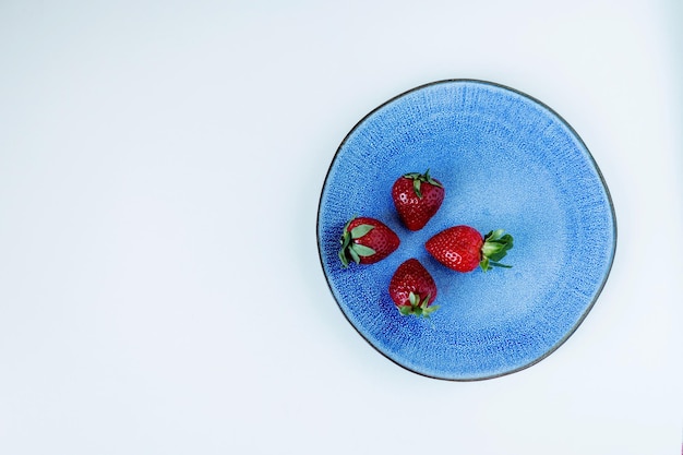 Morangos vermelhos maduros em um prato azul