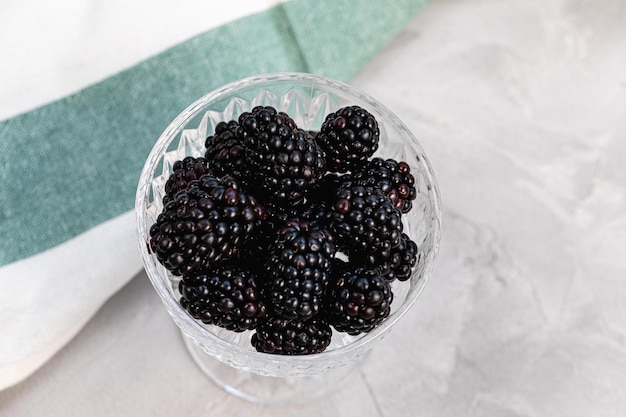 Moras frescas en un recipiente de vidrio estampado sobre fondo gris