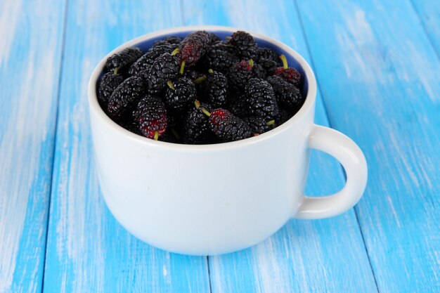 Foto moras maduras en taza sobre fondo de madera