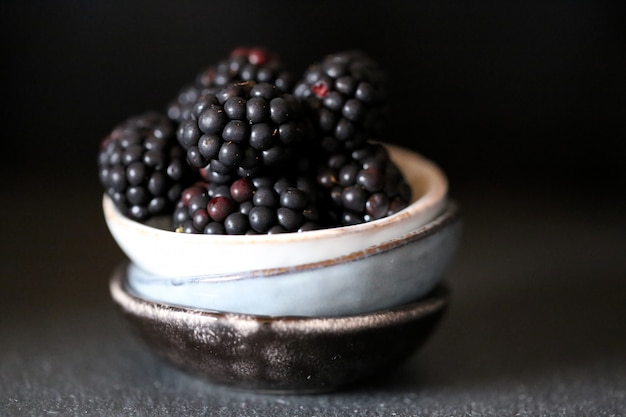 Moras maduras en vasos de barro sobre negro