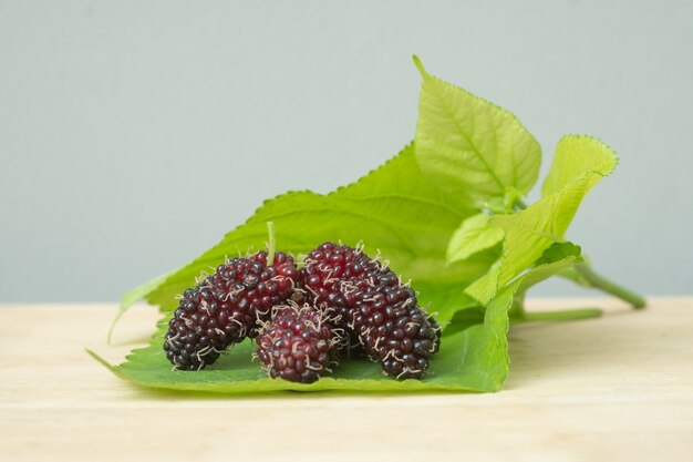 Moras negras con la hoja aislada en la tabla de madera.