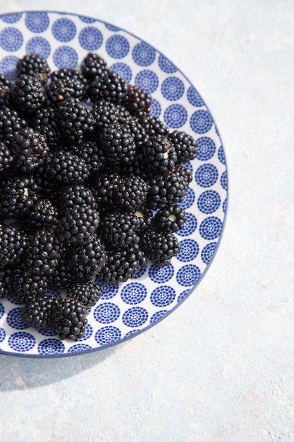 Moras en un plato ligero Orientación vertical de fondo de frutas Primer plano Lugar para un espacio de copia