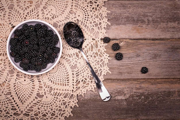 Moras en un recipiente con mantel de encaje y fondo de madera