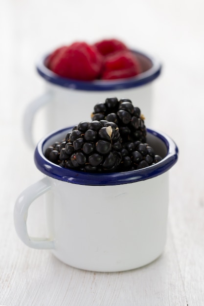 Moras en taza blanca sobre madera azul