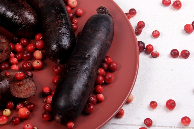 Morcilla al horno en un plato rojo decorado con arándanos rojos