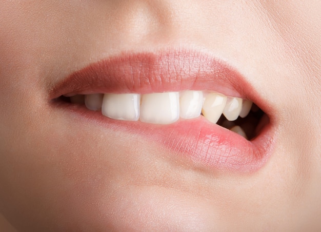 Mordendo os dentes vermelhos dos lábios