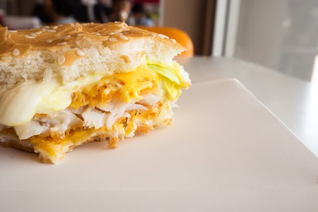 Mordida de queso doble con hamburguesa de pescado frito. En la bandeja del Libro Blanco sobre la mesa en el restaurante.