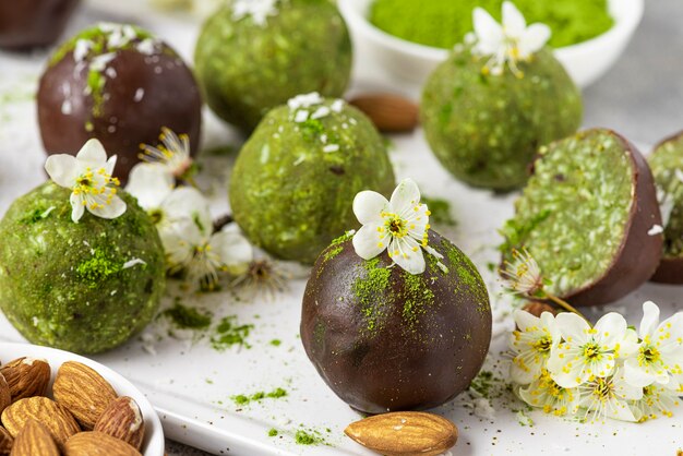 Mordidas ou bolas energéticas matcha em cobertura de chocolate com flores. sobremesa de lanche saudável vegan crua. fechar-se