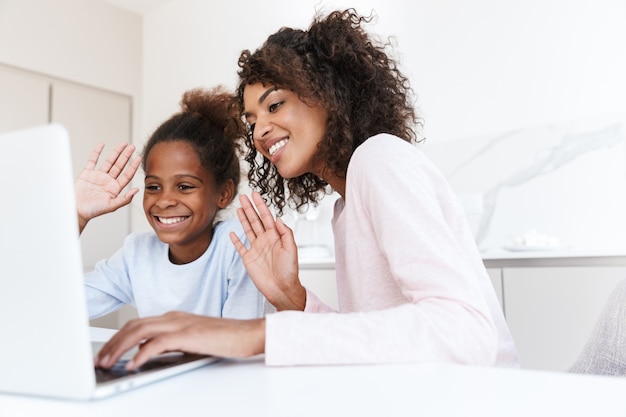Morena afro-americana e sua filha usando o laptop em casa