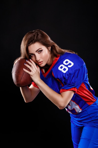 Morena atlética posando como garota de futebol americano em fundo preto