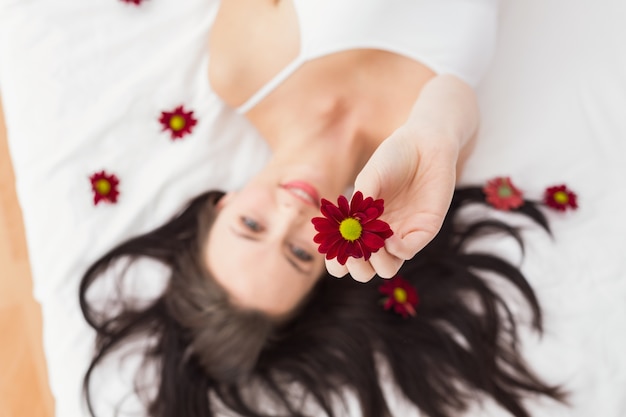 Morena bonita posando na cama com flores