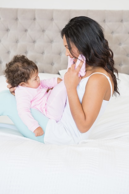 Morena brincando com seu bebê na cama