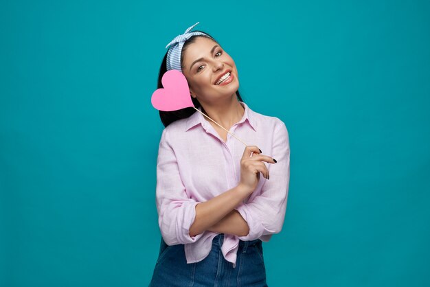 Morena en camisa blanca y jeans manteniendo corazón de papel