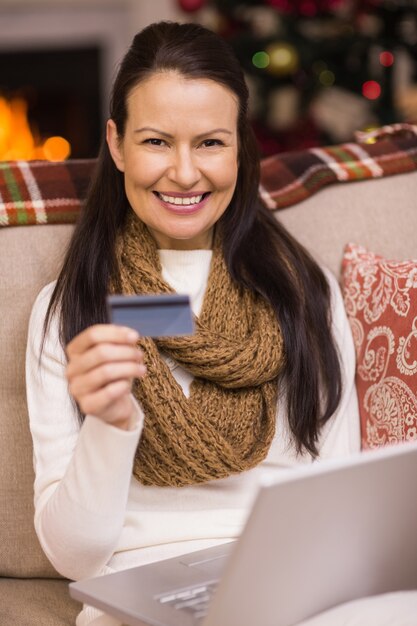 Morena de compras en línea con la computadora portátil en Navidad