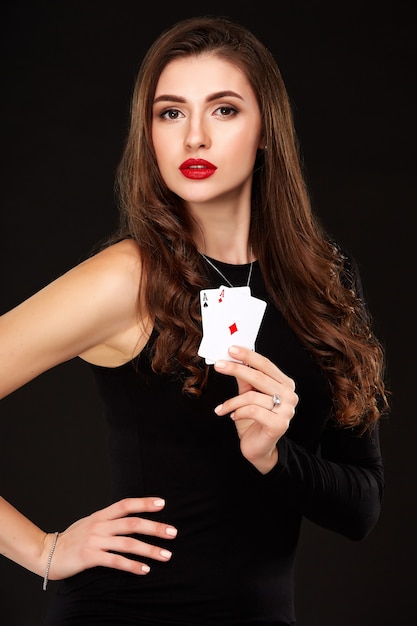 Morena de cabelo encaracolado sexy posando com duas cartas de ases em seu isolamento de conceito de pôquer de mãos em branco ba ...