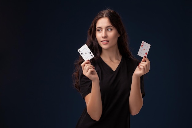 Morena de cabelos cacheados está posando com cartas de jogar. Conceito de pôquer em um fundo preto. Casino.