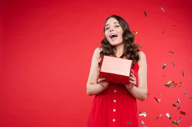 Morena de vestido vermelho, posando enquanto brilhos caindo ao redor