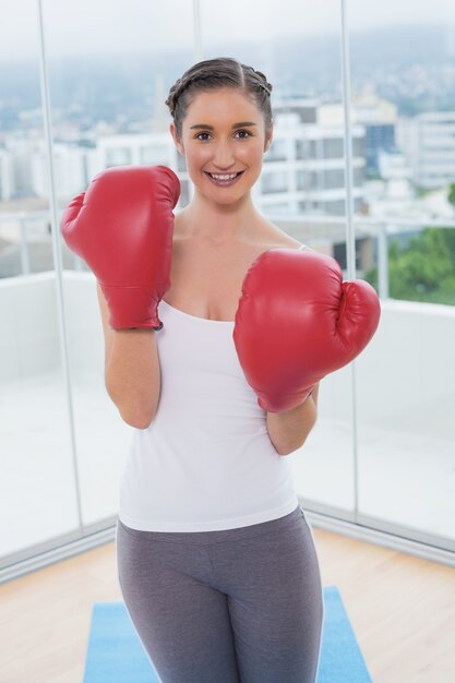 Morena desportiva sorridente que usa luvas de boxe vermelhas