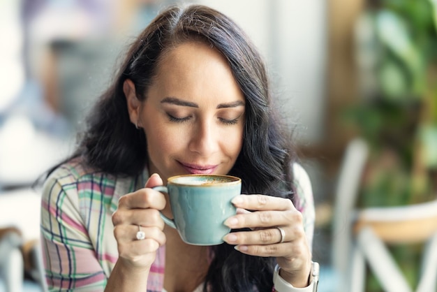 Una morena disfruta del olor del café recién hecho en una cafetería