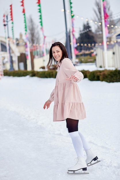 Morena elegante sonriente feliz en vestido de patinaje sobre hielo al aire libre en invierno Estado de ánimo de vacaciones festivas Los sueños se hacen realidad concepto