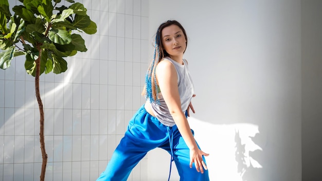 Morena con estilo de danza moderna en pantalones azules holgados bailando al estilo jazzfunk