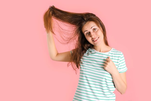 Morena feliz, brincando, penteando o cabelo em um fundo rosa