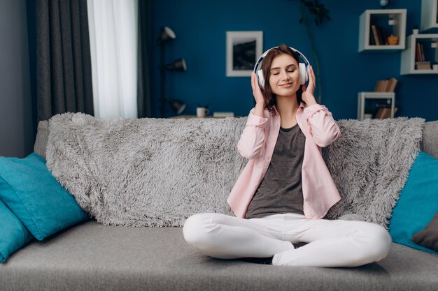 Foto morena feliz ouvindo música em fones de ouvido em casa