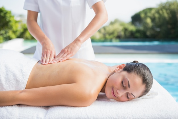 Morena feliz, recebendo uma massagem ao lado da piscina