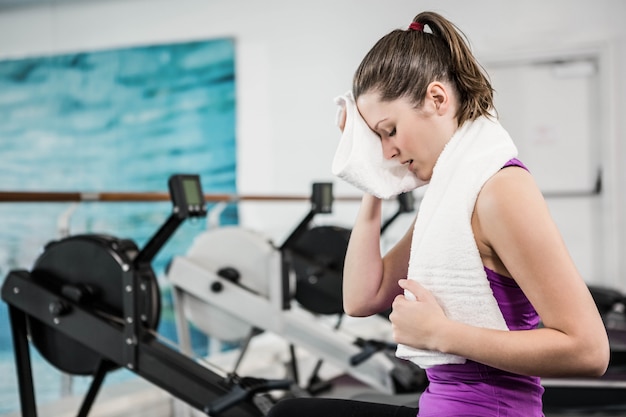 Morena en forma limpia el sudor con una toalla en el gimnasio