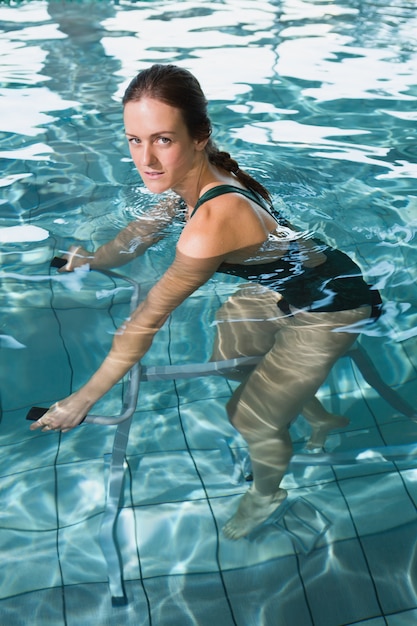 Morena en forma usando bicicleta de ejercicios bajo el agua