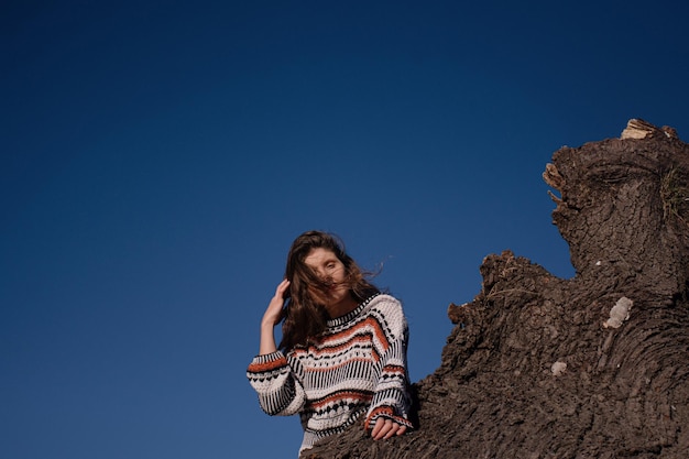 Morena joven atractiva con el pelo largo contra un cielo azul soleado.