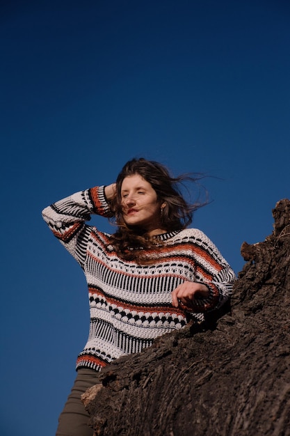 Morena joven atractiva con el pelo largo contra un cielo azul soleado.