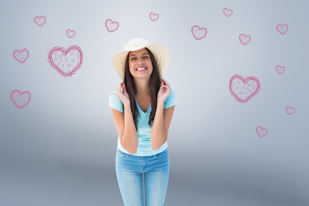 Morena joven feliz con sombrero para el sol contra viñeta gris