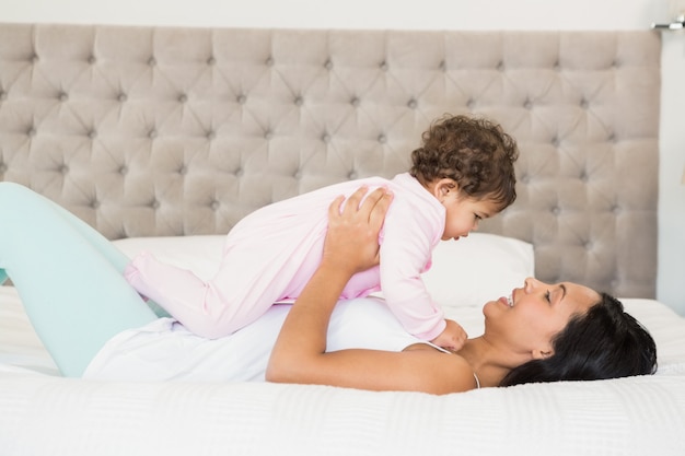 Morena jugando con su bebe en la cama