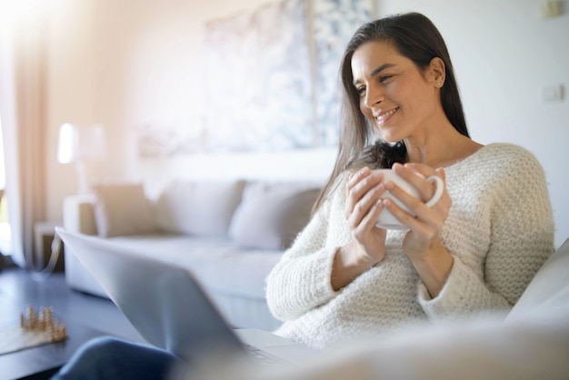 Morena linda descontraída com laptop em casa